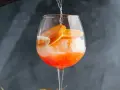 Orzeźwiający drink z cydrem, lodem i plasterkami pomarańczy, przygotowywany w dużym kieliszku.