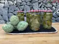 Alcachofas frescas y en conserva en frascos, sobre una mesa de madera y fondo de piedra.