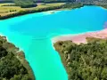 Niezwykłe, turkusowe błękitne jezioro w Koninie otoczone zielenią i piaszczystymi brzegami.