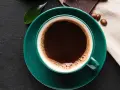 Aromatic coffee in a green cup, next to chocolate and beans. Czy kawa podnosi kortyzol? This morning brew might be the answer.