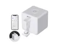 A white cube-shaped device with a robotic arm, paired with a smartphone app, showcasing cool IoT devices for smart home automation.