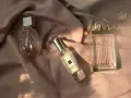 Drei Parfümflaschen auf rosafarbenem Stoff, im Sonnenlicht.