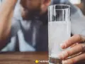 Mężczyzna trzyma szklankę z musującym napojem, szukając sposobu, jak szybko wytrzeźwieć.