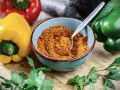 Schüssel mit Gewürzmischung zum **pul biber selbst mischen**. Bunte Paprika und Petersilie liegen daneben.