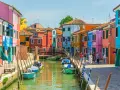 Colorate case affacciate su un canale a Venezia, con barche ormeggiate e persone che passeggiano. Le fondamenta sono un tripudio di colori vivaci.