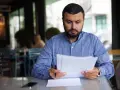 Mężczyzna w niebieskiej koszuli analizuje dokumenty, być może przygotowując wniosek o umorzenie postępowania egzekucyjnego.