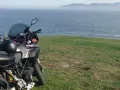 Motocykl Ducati zaparkowany na trawie z widokiem na morze. Marzenie o podróży przez Szwecję motocyklem.