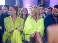 Dwie kobiety w stylizacjach w kolorze limonkowym siedzą w pierwszym rzędzie.