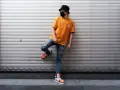 Chłopak w pomarańczowej koszulce, zniszczonych jeansach i modnych sneakersach, w czarnej czapce i masce. To stylówka, która przypomina, y2k co to za moda?
