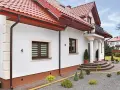 Elegancki dom z białym tynkiem i brązowymi detalami. Cokół wykończony ozdobnym tynkiem mozaikowym dodaje mu charakteru.