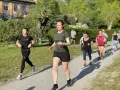 En grupp löpare på en grusväg, en del med fokus på att få upp konditionen snabbt. Solen skiner och träden är gröna.