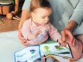 Baby lernt mit einem Stoffbuch und Musikinstrumenten. Förderung der sprachentwicklung baby.