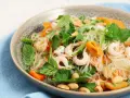 En läcker asiatisk nudelsallad med räkor, morötter, gurka, jordnötter och färska örter.