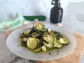 Piatto di zucchine alla scapece, fette sottili condite con olio, aglio e prezzemolo.