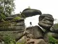 Turysta stoi na skale pod skalnym łukiem w Broumovskich Ścianach.