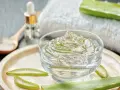 Un bol de gel aloe vera, des tranches d'aloe vera et une cuillère en bois. Découvrez les bienfaits du gel aloe vera pour votre peau.
