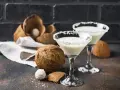 Malibu z mlekiem czy Malibu z sokiem ananasowym? Dwa koktajle w kieliszkach, obok kokosy i deserki.