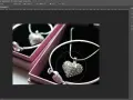 Un collier en forme de cœur orné de strass, dans une boîte rose. Un effet lumière Photoshop est appliqué pour le faire scintiller.