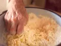 Dłoń miesza mąkę z jajkami, przygotowując ciasto na makaron domowy przepis babci.