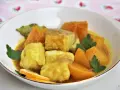 Sabroso cazon en amarillo, con trozos de pescado blanco y patatas en una salsa dorada, decorado con perejil y rodajas de limón.