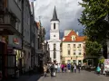 Ulica w jednym z miast na zachodzie Polski, z kościołem w tle i ludźmi spacerującymi po rynku.