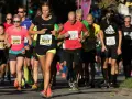 Kvinnlig löpare i täten under Stockholm tempo halvmaraton. Många löpare i olika färger på kläderna.