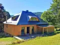 Drewniany domek z niebieskim dachem, tarasem i zielonymi okiennicami. Idealne schronisko oźna na górskim stoku.