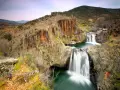 Cascadas en el río Guadalajara, rodeadas de rocas rojizas y vegetación otoñal.