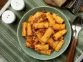 Pyszne makaron grube rurki z sosem bolońskim i parmezanem, gotowe do jedzenia.