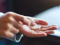 Dłoń trzyma białe kapsułki. Zastanawiasz się nad przedawkowanie witaminy b12 objawy?