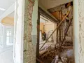 Trwa remont domu. Widać rozbiórkę ścian, gruz i pracowników na drabinach.