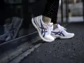 Vita Asics-skor med blå och röda detaljer, perfekt för löpning. Kolla in vår asics storleksguide för rätt passform.