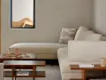 Sofá modular beige, mesa de centro de madera con juego de Jenga, planta en maceta y ventana con detalle decorativo. Ambiente de estilo cozy.