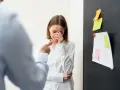 Mujer llora mientras un colega la señala, sufriendo acoso laboral.