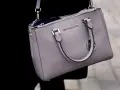 Szara torebka Michael Kors, znanej firmy z luksusowymi akcesoriami, z widocznym logo.