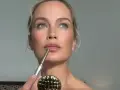 Kobieta z błękitnymi oczami precyzyjnie wykonuje makijaż wieczorowy, podkreślając usta konturówką.