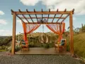 En vacker träpergola med orange draperier och hängstol. Perfekt för att bygga pergola på altan och njuta av utsikten.