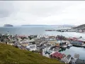 Vy över en stad vid havet med färjor vid kaj. En kyrka med högt torn syns i förgrunden. Detta är Norges nordligaste stad.