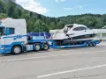 Ein LKW transportiert ein luxuriöses Boot auf einem Spezialanhänger. Die Yacht ist sicher auf dem Anhänger befestigt, bereit für den Transport über Land.