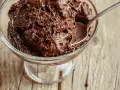 Une cuillère s'enfonce dans une coupe de mousse au chocolat au lait onctueuse, prête à être dégustée.