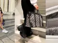 Kobieta w pastelowej sukience i sportowych butach prezentuje różową christian dior torebkę. Obok, inna torebka Dior w granatowe monogramy.