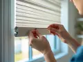 Hands carefully attach a blind to a window frame, demonstrating how to install blinds for a clean, modern look.