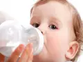 Małe dziecko pije z butelki, która może służyć jako butelka do mleka dla 3 latka.