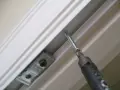 Screwdriver installing a bracket for how to install bifold doors.