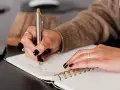 Kredytobiorca pisze w notatniku, planując swoje finanse.