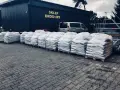 Duże worki z materiałem budowlanym przed sklepem drogowym. Zastanawiasz się, ile kosztuje asfalt? Tutaj znajdziesz odpowiedź.