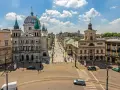 Widok na ulicę Piotrowską w Łodzi, z kościołem św. Stanisława Kostki i kamienicami. Tętniące życiem łódzkie stare miasto w słoneczny dzień.