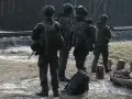 Szeregowi w wojsku patrolują teren przy torach kolejowych, gotowi do akcji.