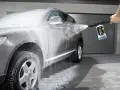 En bil tvättas med högtryckstvätt och Kärcher bilschampo. Skum täcker bilen medan den rengörs.
