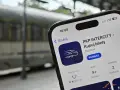 Telefon z aplikacją PKP Intercity na tle pociągu.